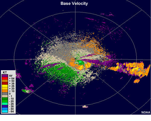 Radar velocity showing a large area of strong outbound velocities aligned with a cluster of thunderstorms, with an adjacent small region of strong inbound velocities that is slightly closer to the radar