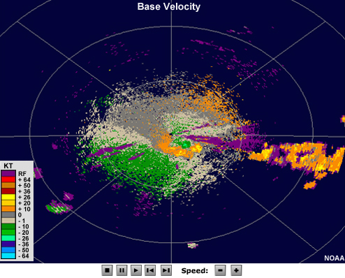 Radar velocity showing a large area of strong outbound velocities aligned with a cluster of thunderstorms, with an adjacent small region of strong inbound velocities that is slightly closer to the radar